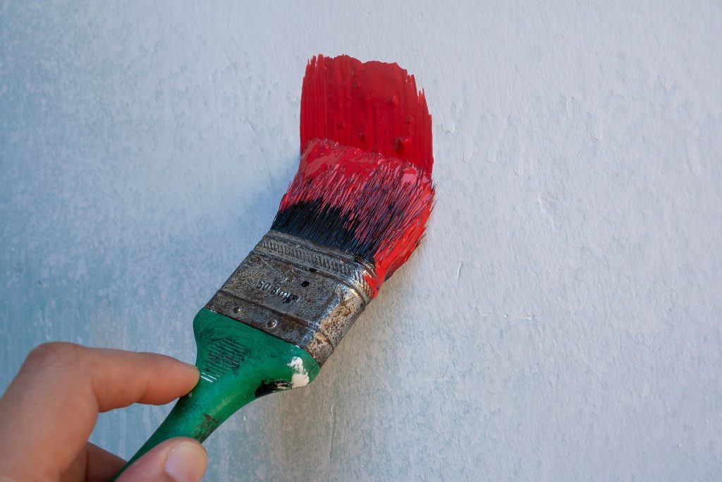 close-up of a person painting a white wall red