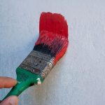 close-up of a person painting a white wall red